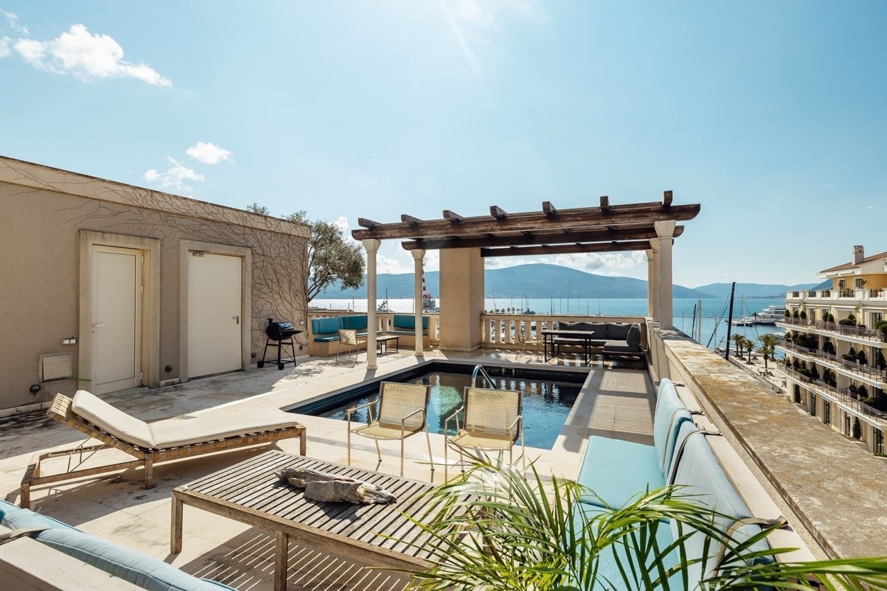 Terrace with a pool and marina view in Porto Montenegro, Tivat, Montenegro: sun loungers, pergola, and lounge area.