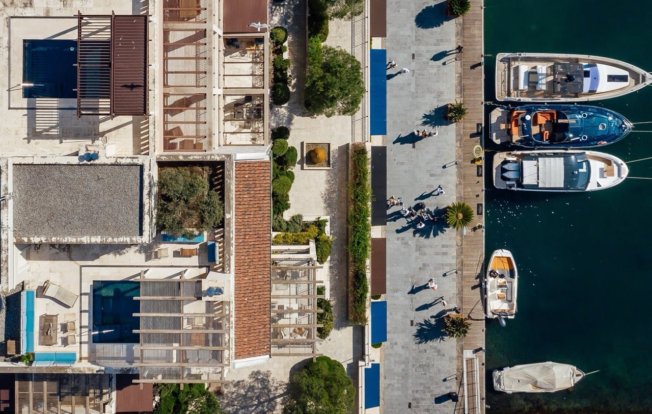 Top view of luxury apartments and a marina with yachts in Porto Montenegro, Tivat, Montenegro: terraces, pools, and the waterfront.