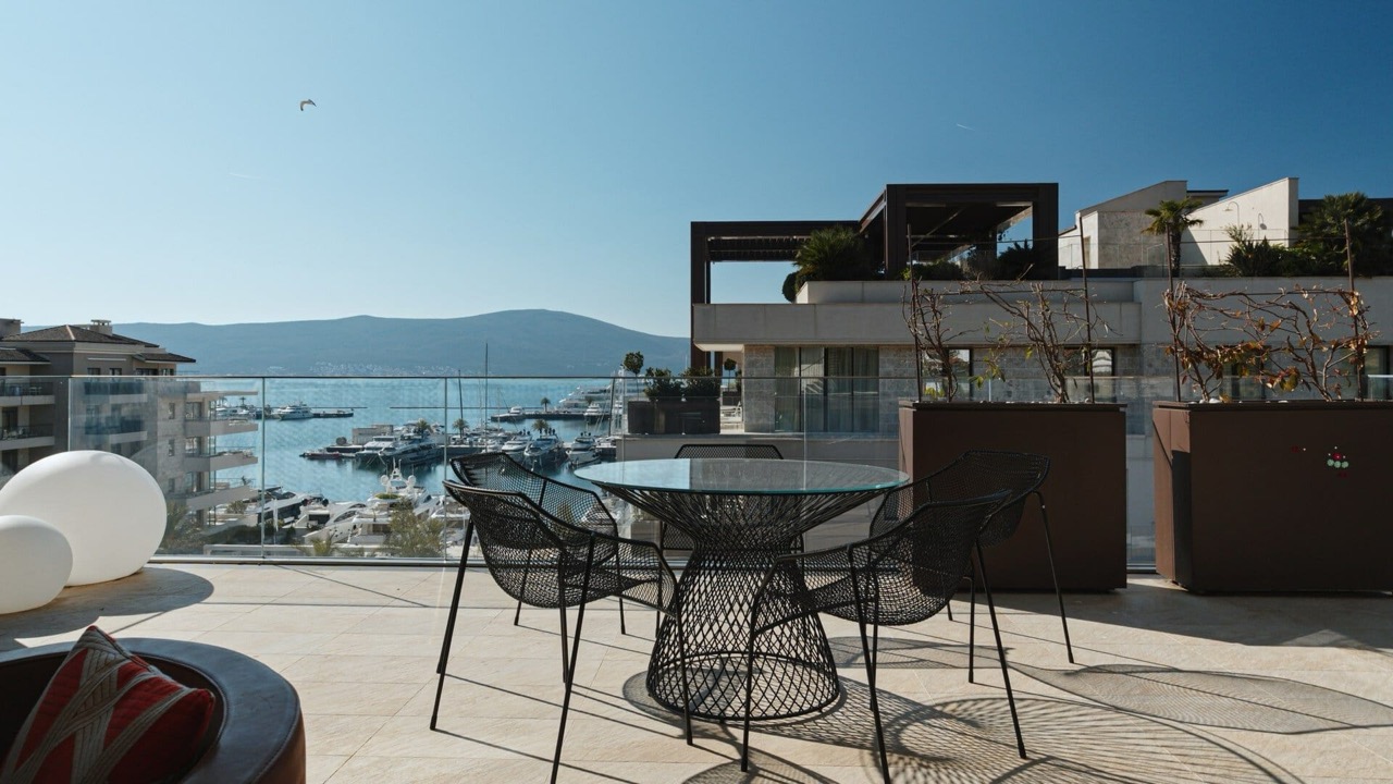 Terrace with furniture and views of the marina and yachts in Porto Montenegro, Tivat, Montenegro. Modern balcony with a sea panorama.