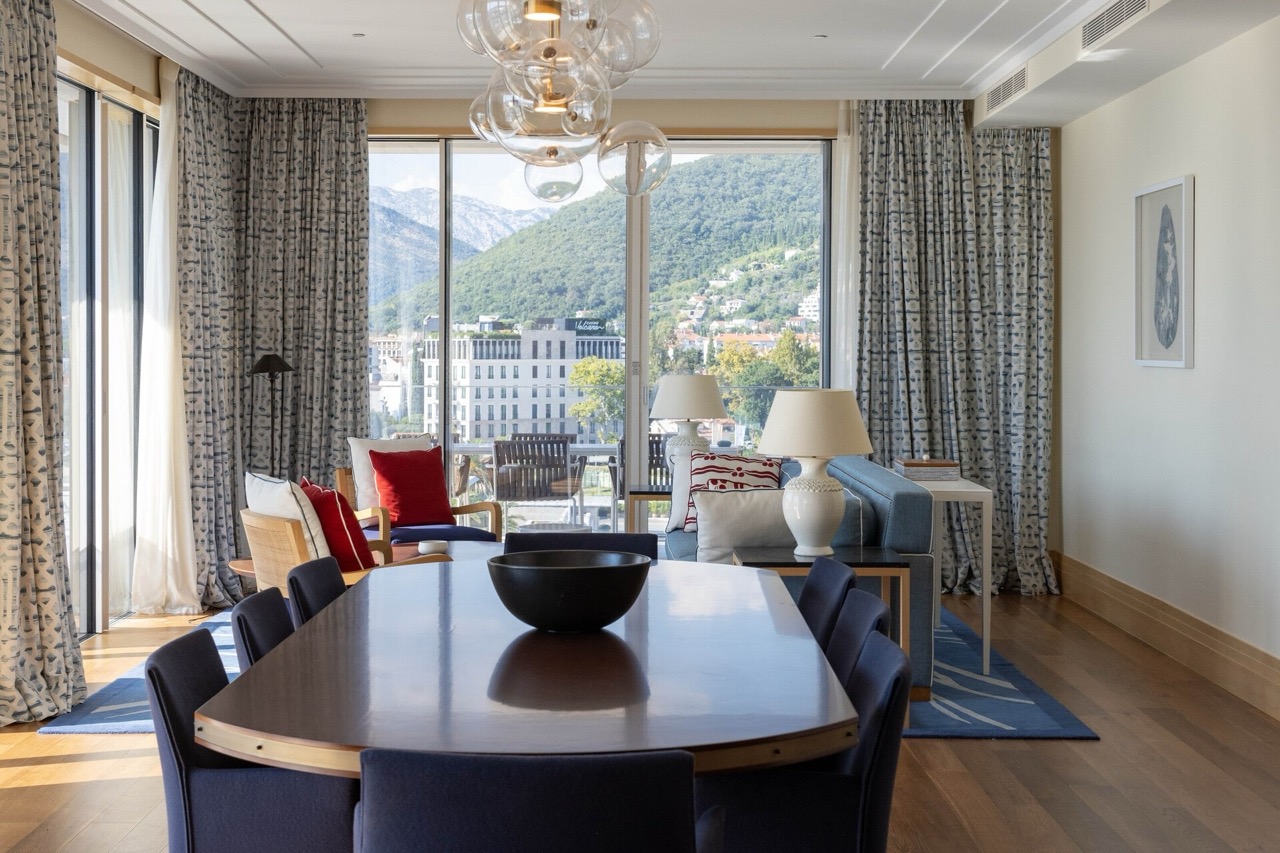 Living room with dining area in an apartment in Tivat, Montenegro: panoramic mountain view, modern furniture and decor.