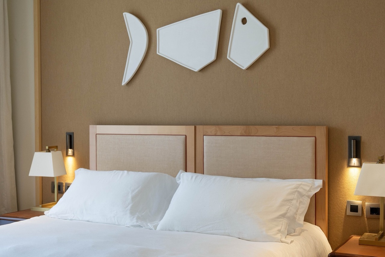 Modern bedroom in an apartment in Tivat, Montenegro: a double bed, beige headboard, and fish-themed decor.