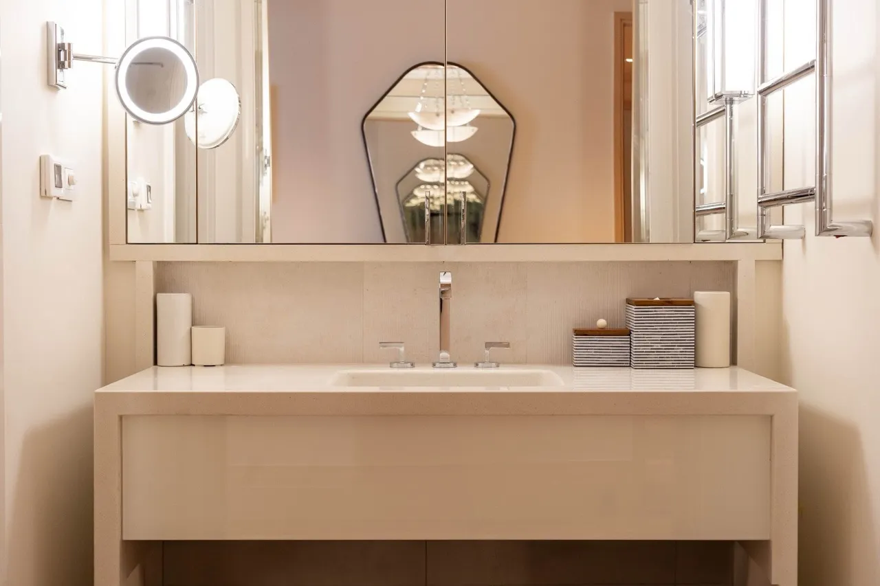 Modern bathroom featuring a white vanity sink, large mirror, and a magnifying wall-mounted mirror.