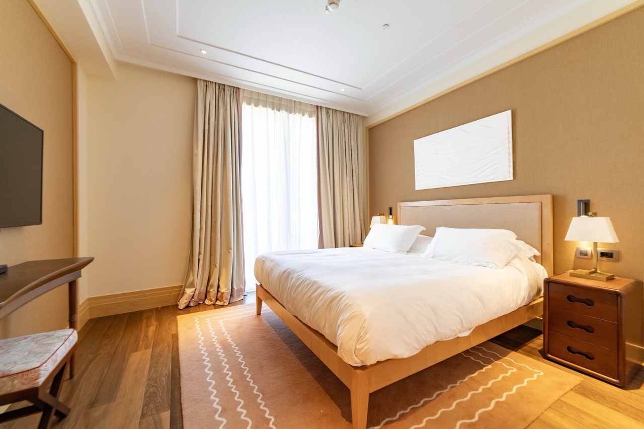 Cozy bedroom with a double bed in an apartment in Tivat, Montenegro: modern interior, parquet flooring, and panoramic windows.