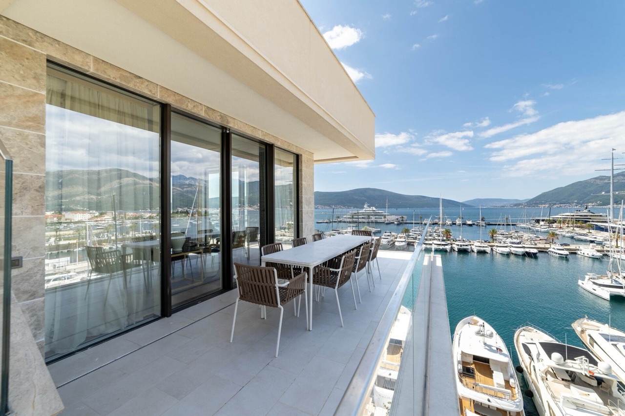 Terrace with dining area and views of Porto Montenegro marina, Tivat, Montenegro: modern furniture and panoramic windows.
