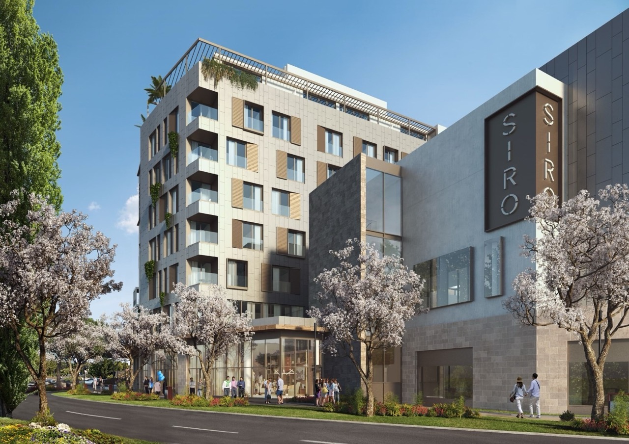 Modern Siro hotel building in Porto Montenegro, Tivat, Montenegro: facade with panoramic windows and blooming trees.