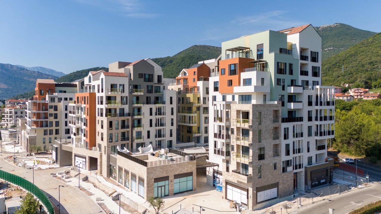 Modern residential complex in Porto Montenegro, Tivat, Montenegro: view of multi-story buildings with terraces and mountains.