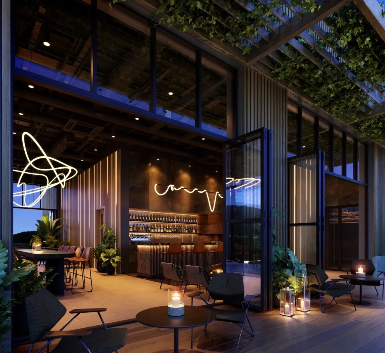 Modern bar with an open terrace, wooden decking, plants, and stylish lighting at night.