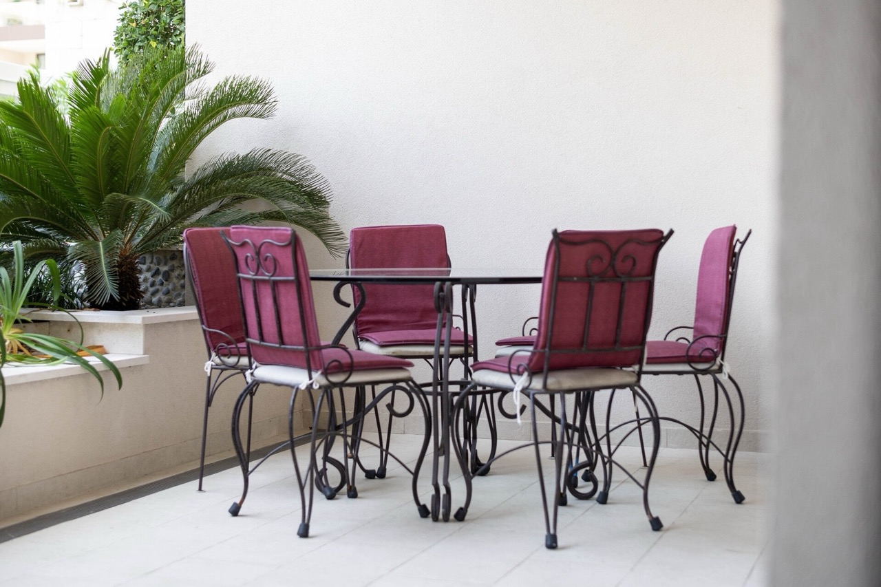 Cozy terrace with wrought-iron furniture and a palm tree in an apartment in Porto Montenegro, Tivat, Montenegro.