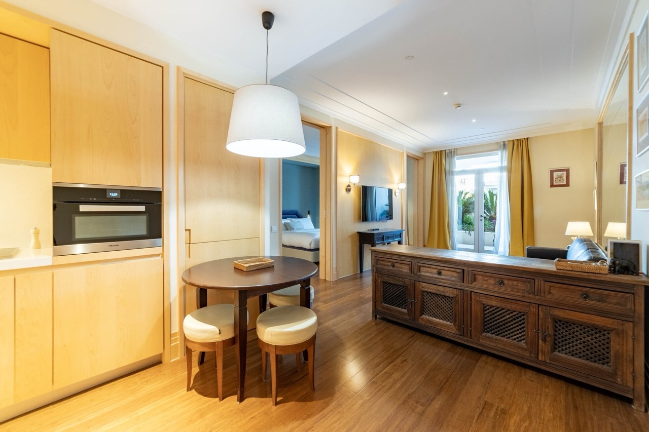 Living room with kitchen in Porto Montenegro apartments, Tivat, Montenegro: wooden furniture, dining area, and terrace.