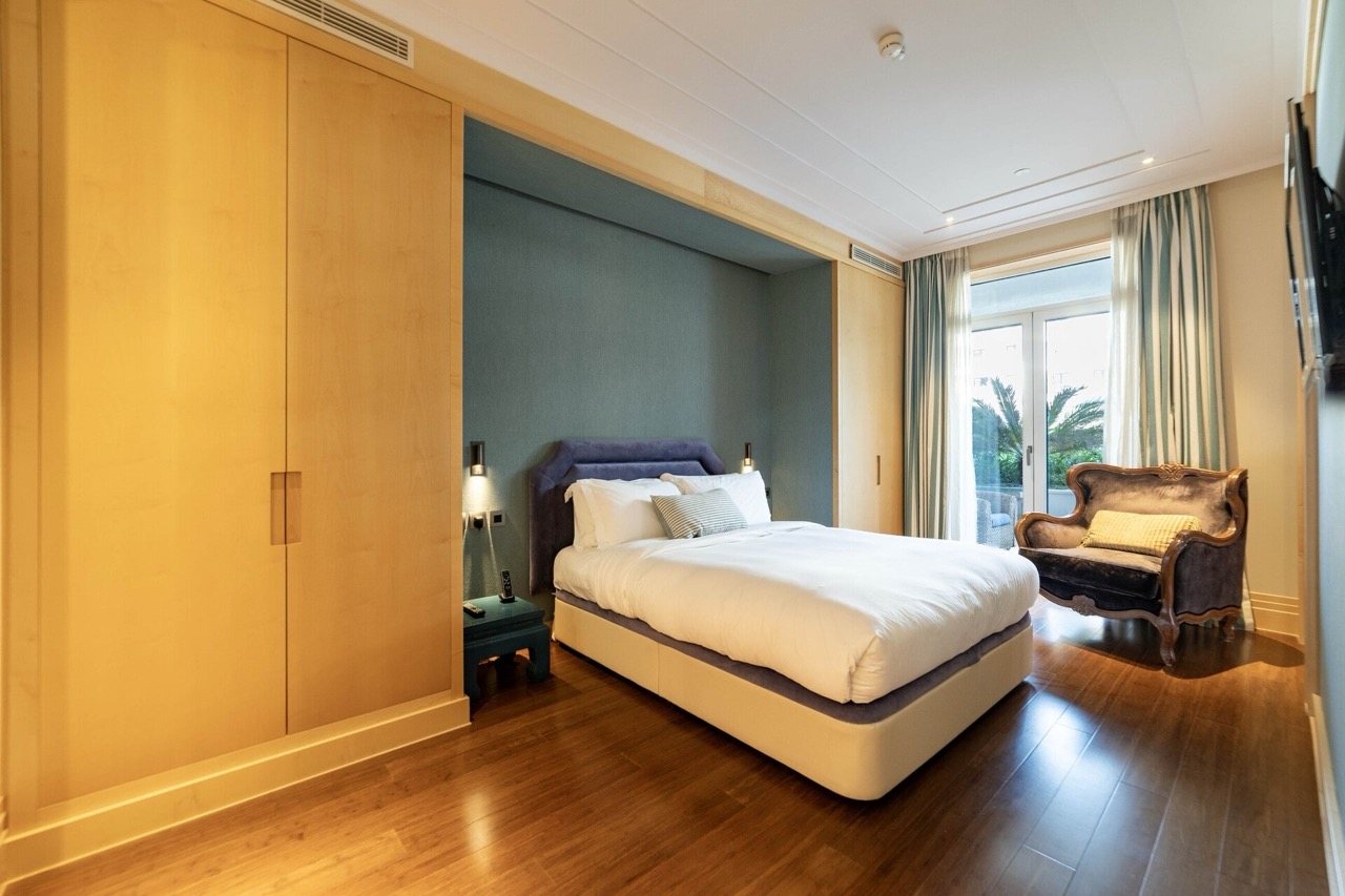 Bedroom in an apartment in Porto Montenegro, Tivat, Montenegro: double bed, wooden wardrobes, and an armchair by the window.