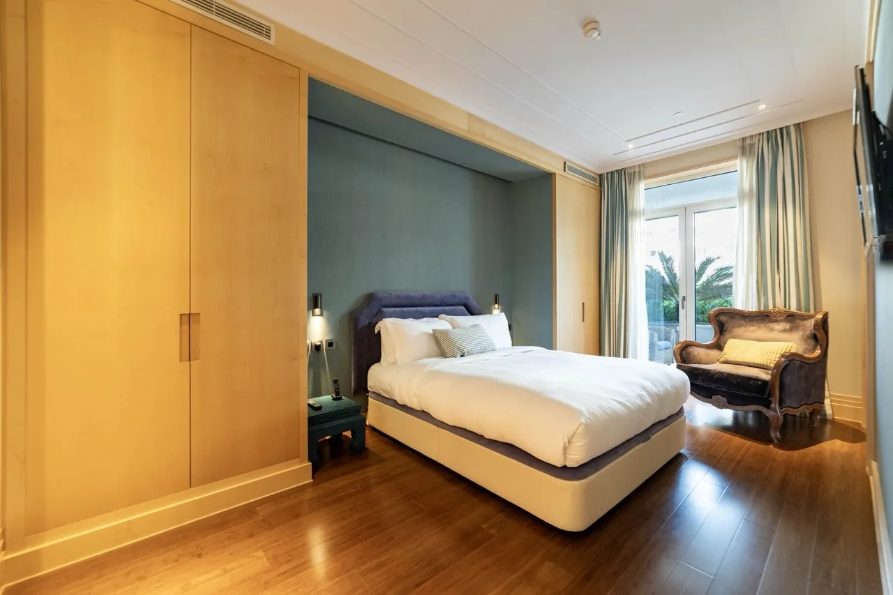 Bedroom featuring a large bed, light wood wardrobe, and blue accent wall.