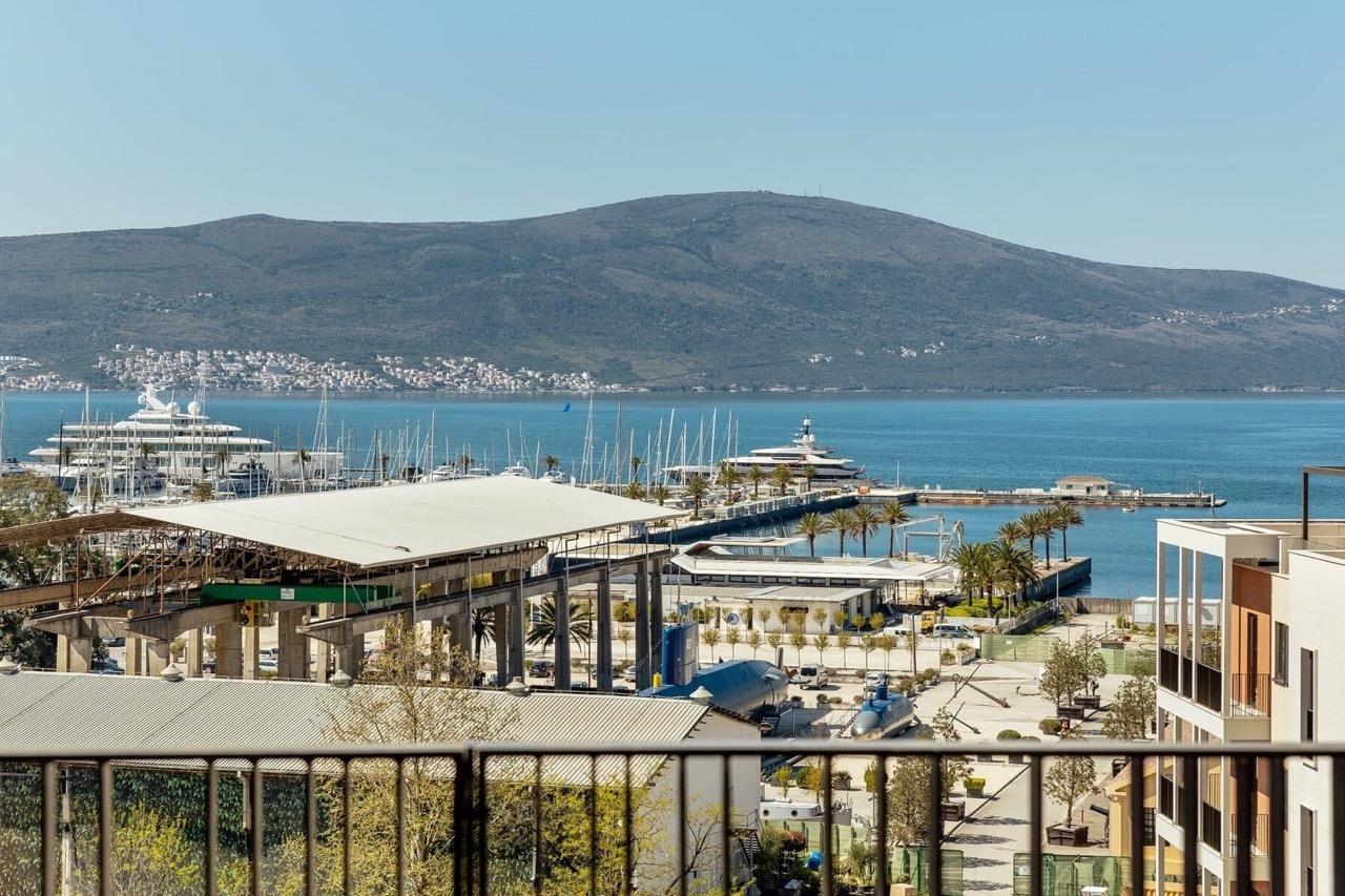 View from the apartment balcony in Porto Montenegro, Tivat: panoramic view of the marina with yachts, the sea, and the mountains of Montenegro.