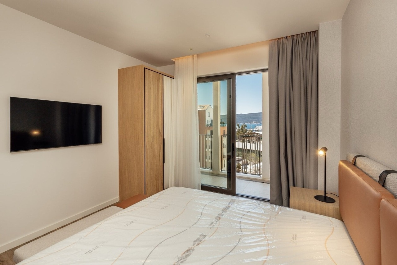 Modern bedroom in Porto Montenegro, Tivat, Montenegro: double bed, wardrobe, and sea view from the balcony.