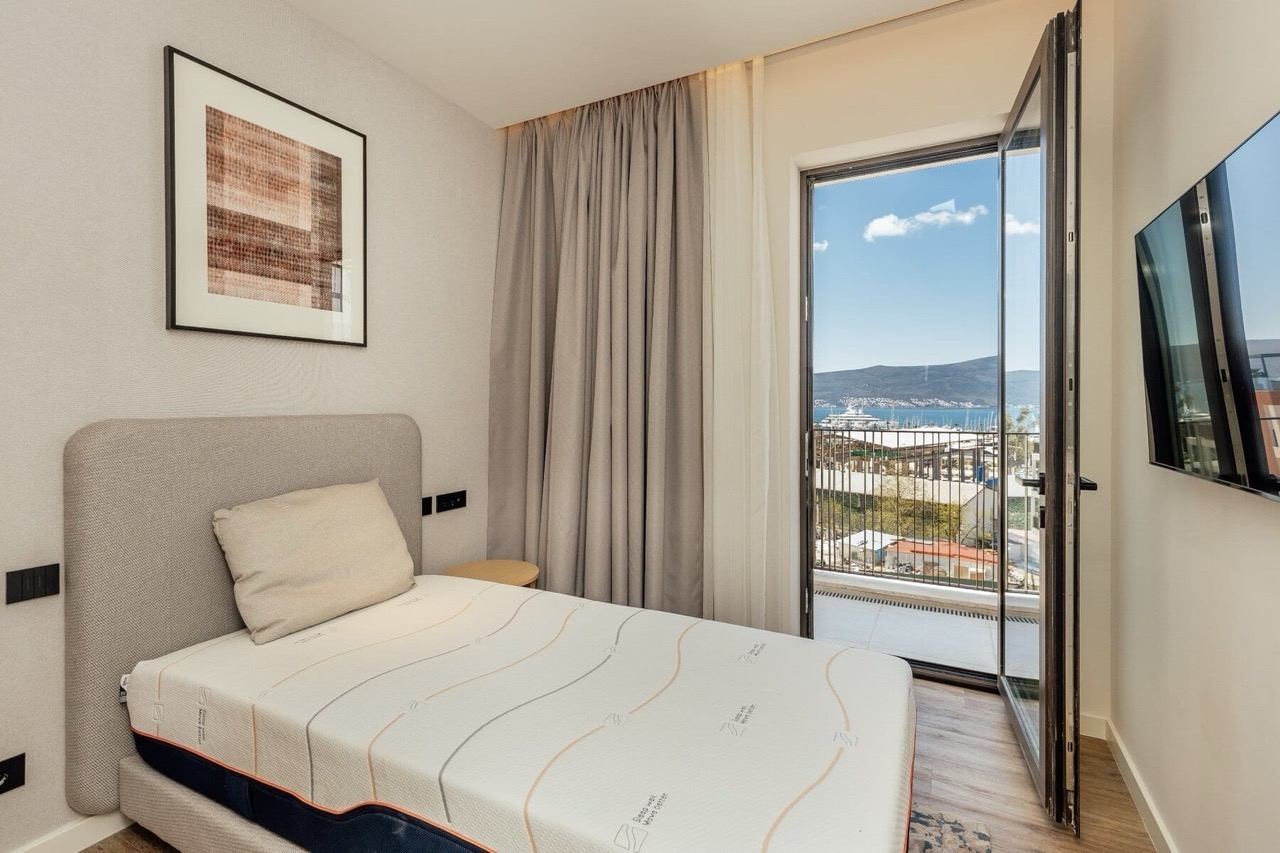 Bedroom in an apartment in Porto Montenegro, Tivat, Montenegro: bed, TV, and a balcony with a view of the marina and the sea.