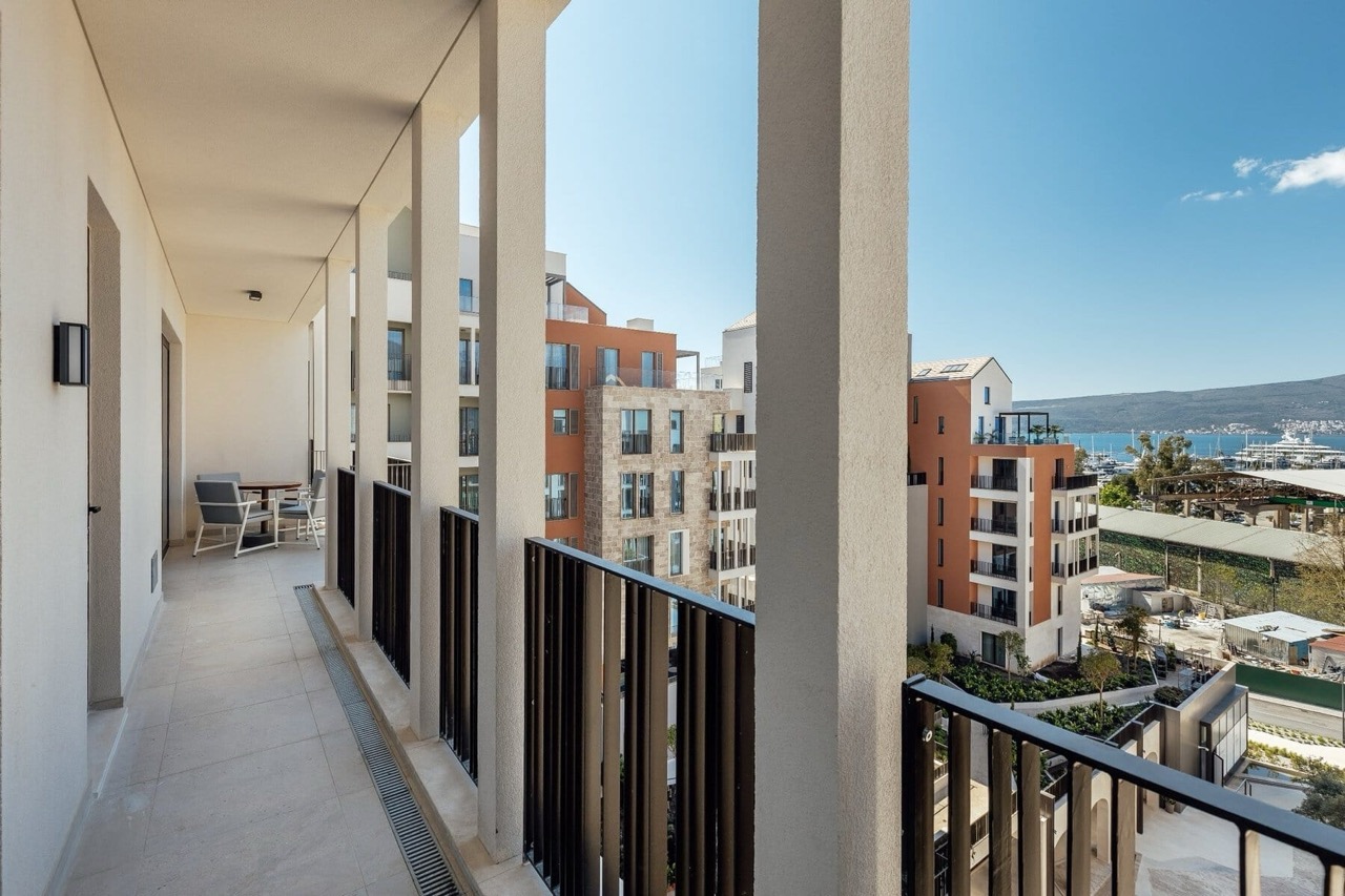 Spacious balcony with furniture in the luxury Porto Montenegro residential complex, Tivat, Montenegro, overlooking the marina and modern buildings.