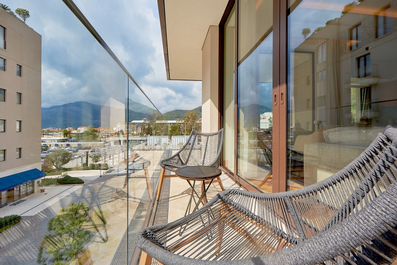 Balcony with wicker furniture in Porto Montenegro apartments, Tivat, Montenegro, overlooking the mountains and the marina.