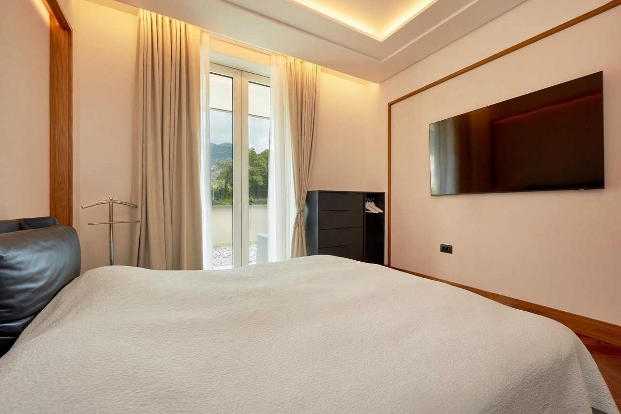 Modern bedroom in an apartment in Porto Montenegro, Tivat, Montenegro: double bed, TV, and mountain view.