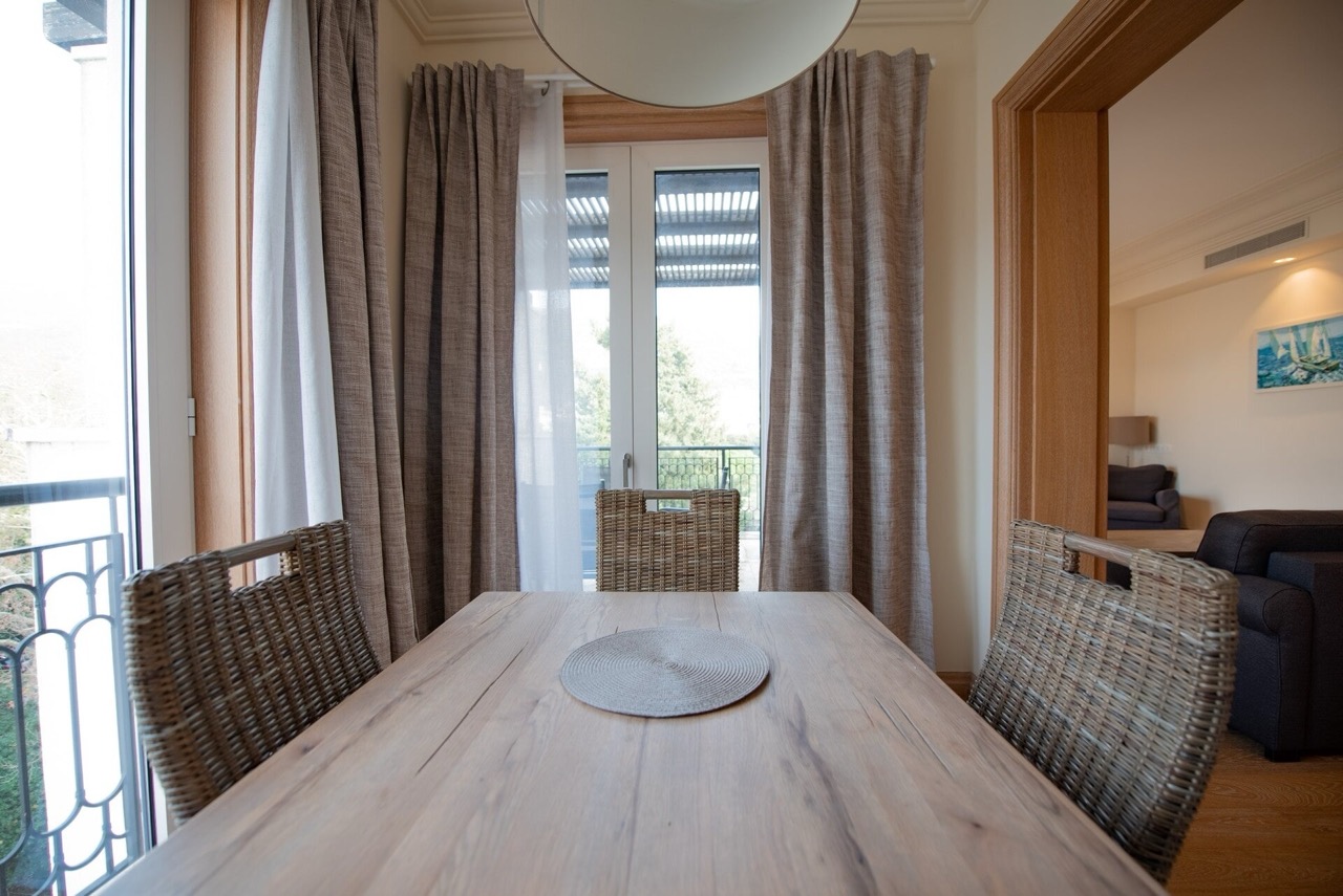 Dining area with a wooden table and wicker chairs in an apartment in Porto Montenegro, Tivat, Montenegro.