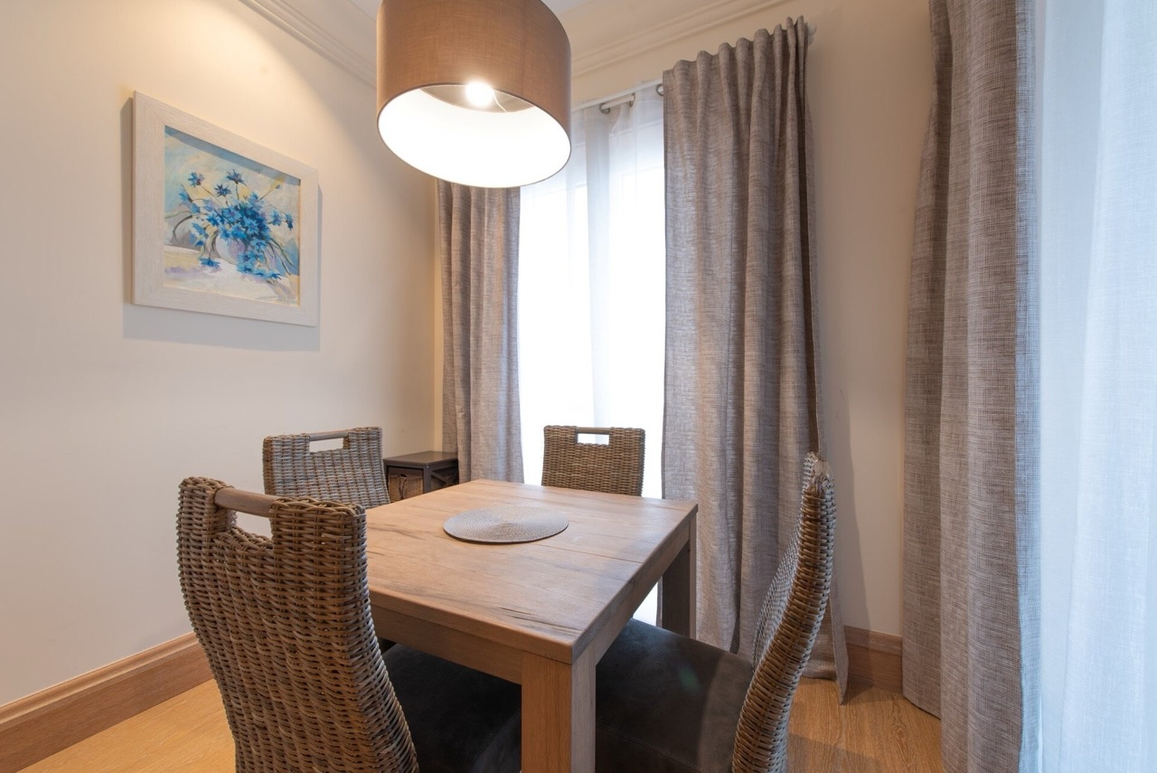 Dining area with a wooden table and wicker chairs in an apartment in Porto Montenegro, Tivat, Montenegro.