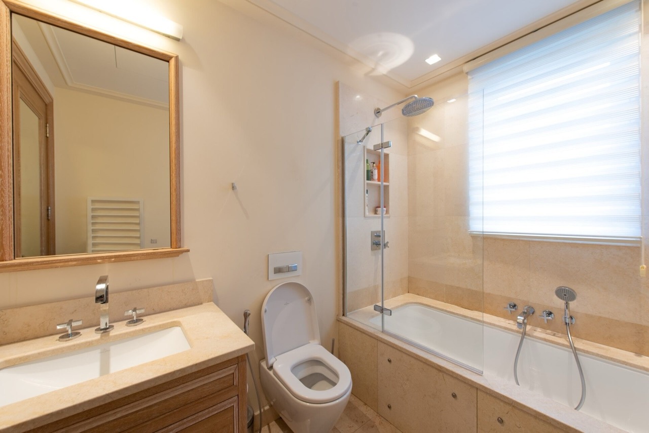 Modern bathroom with stone finishes in an apartment at Porto Montenegro, Tivat, Montenegro: bathtub and shower.