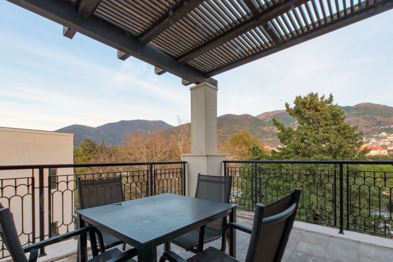Terrace with furniture and mountain views in an apartment in Porto Montenegro, Tivat, Montenegro. Balcony with an awning and wrought-iron railing.