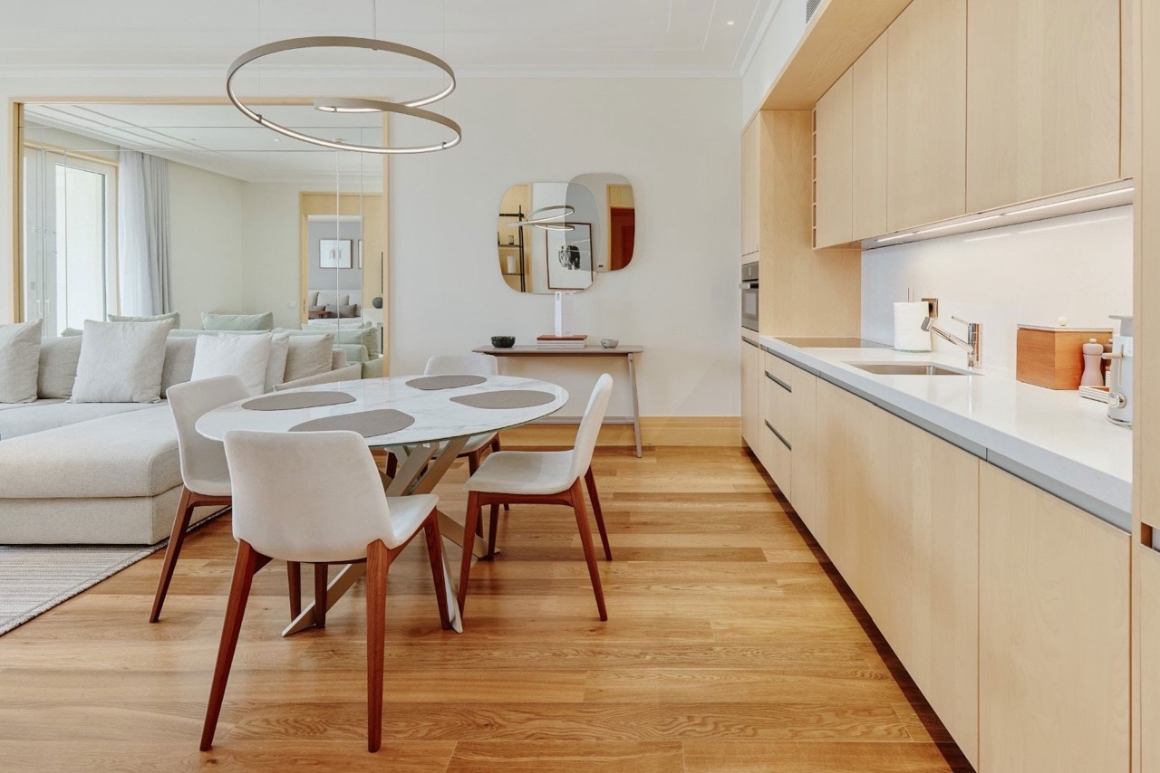 Modern kitchen-dining room in an apartment in Porto Montenegro, Tivat, Montenegro: light furniture, marble table, and parquet flooring.
