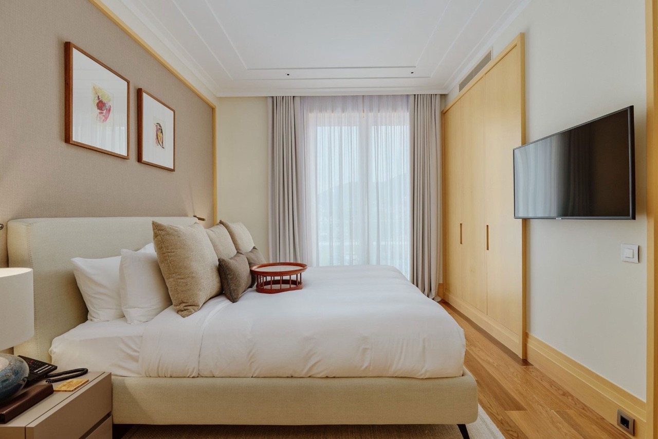 Modern bedroom in an apartment in Porto Montenegro, Tivat, Montenegro: double bed, light-colored furniture, and TV.