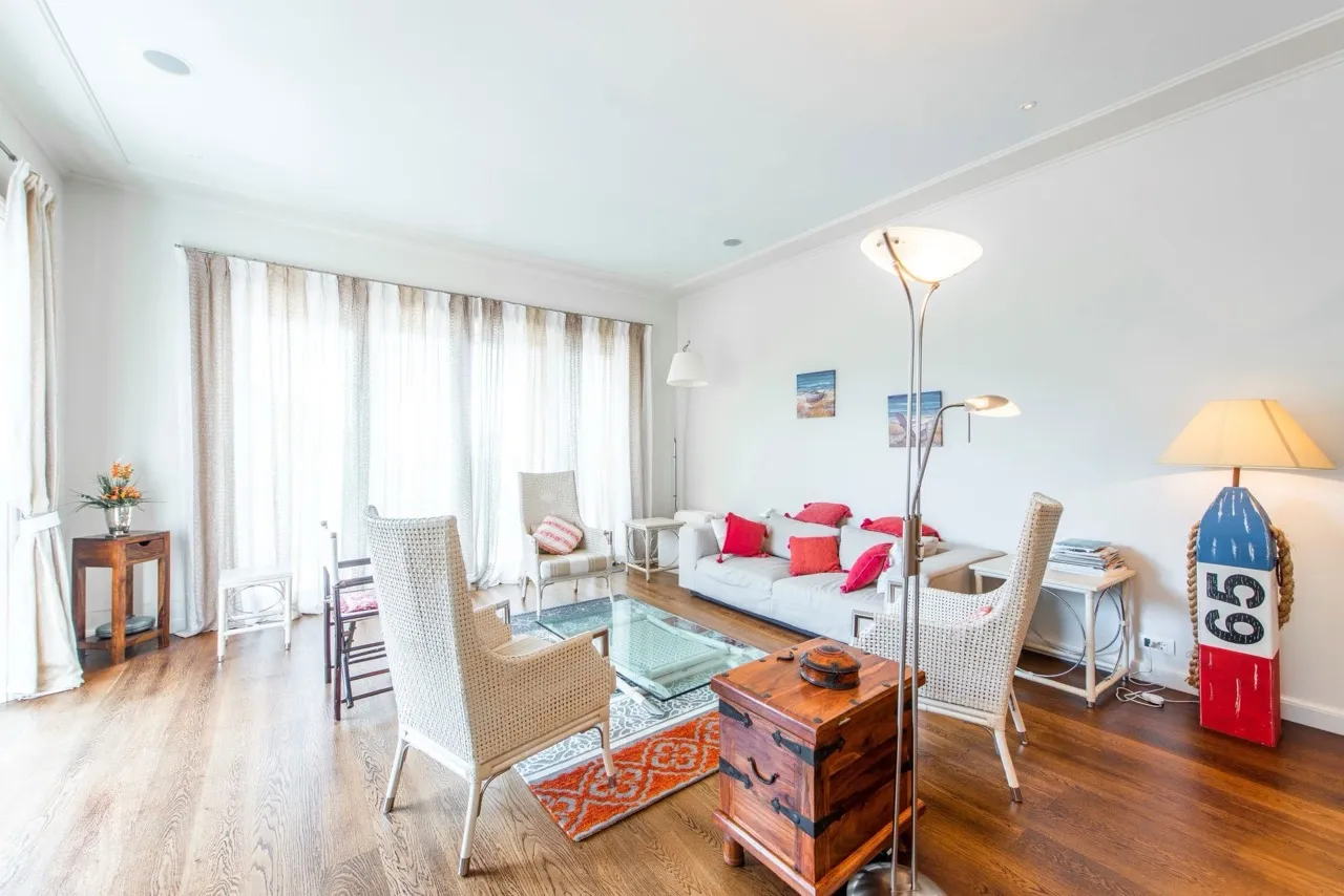 Bright room with a sofa, wicker chairs, hardwood floors, and a decorative buoy lamp.