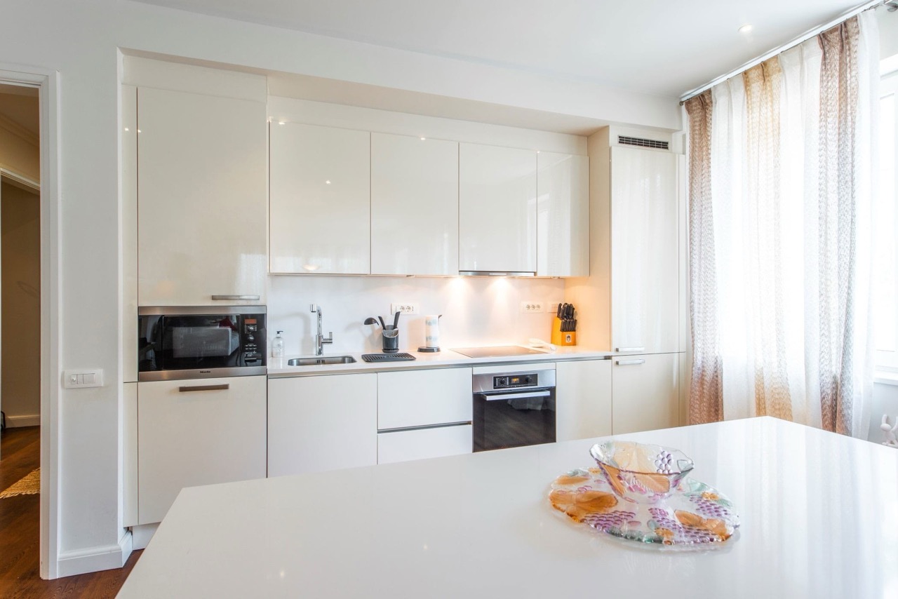 Modern white kitchen in an apartment in Porto Montenegro, Tivat, Montenegro: built-in appliances and glossy cabinet fronts.