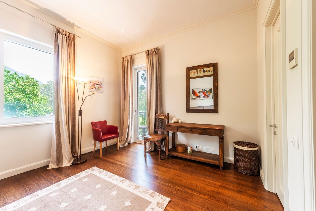Bright living room in an apartment in Porto Montenegro, Tivat, Montenegro: wooden floor, vintage furniture, and a view of greenery.