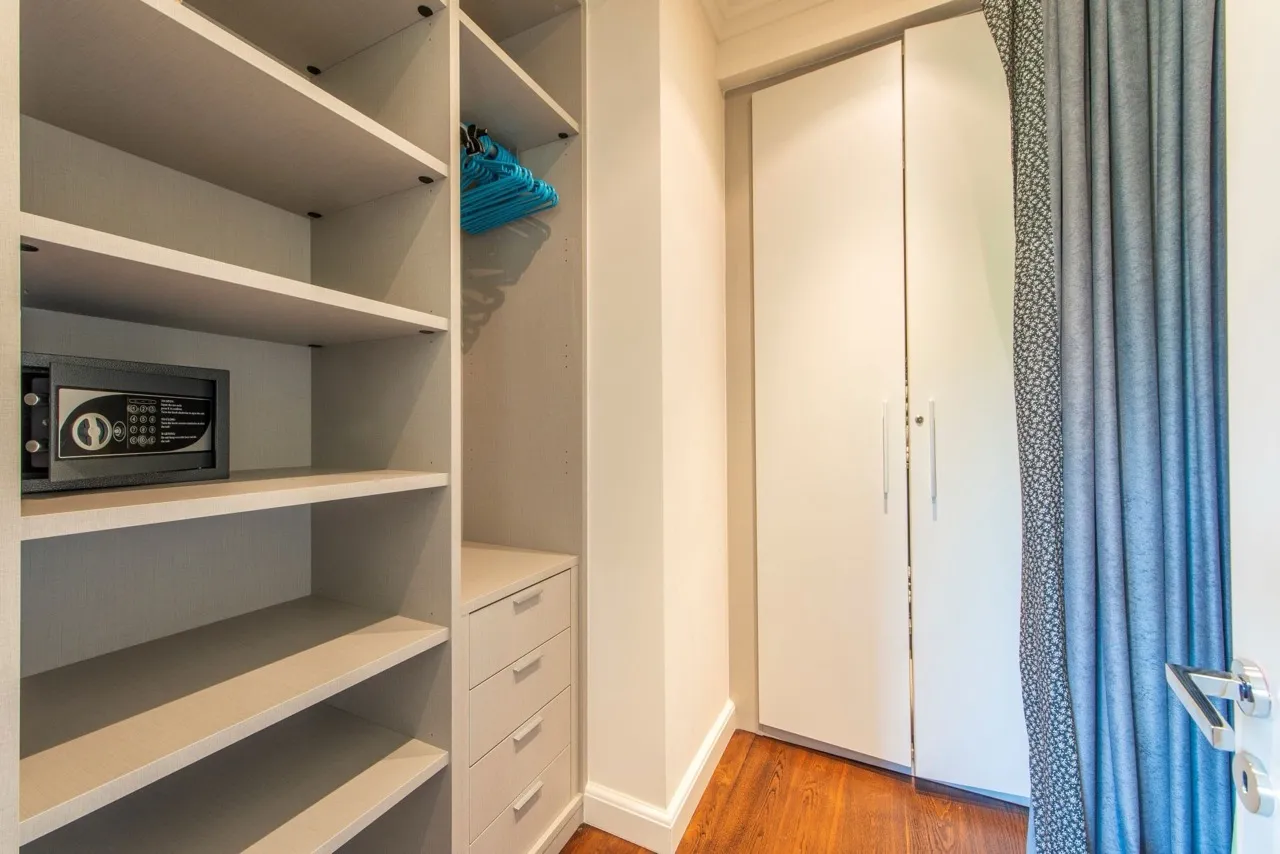 Built-in closet with shelves, drawers, a safe, and blue hangers for clothes.