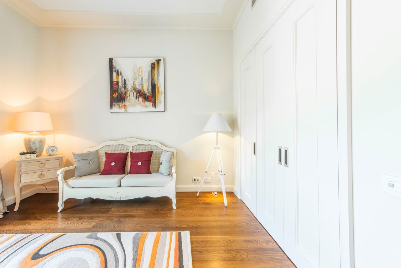 Living room in an apartment in Porto Montenegro, Tivat, Montenegro: light-colored furniture, built-in wardrobe, and parquet flooring.