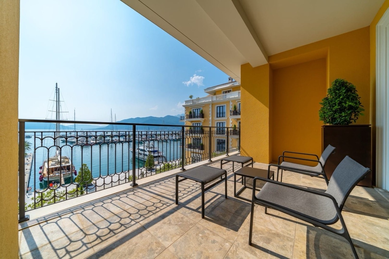 Balcony with furniture and a view of the yacht marina in Porto Montenegro, Tivat, Montenegro: terrace with tile flooring and sea view.
