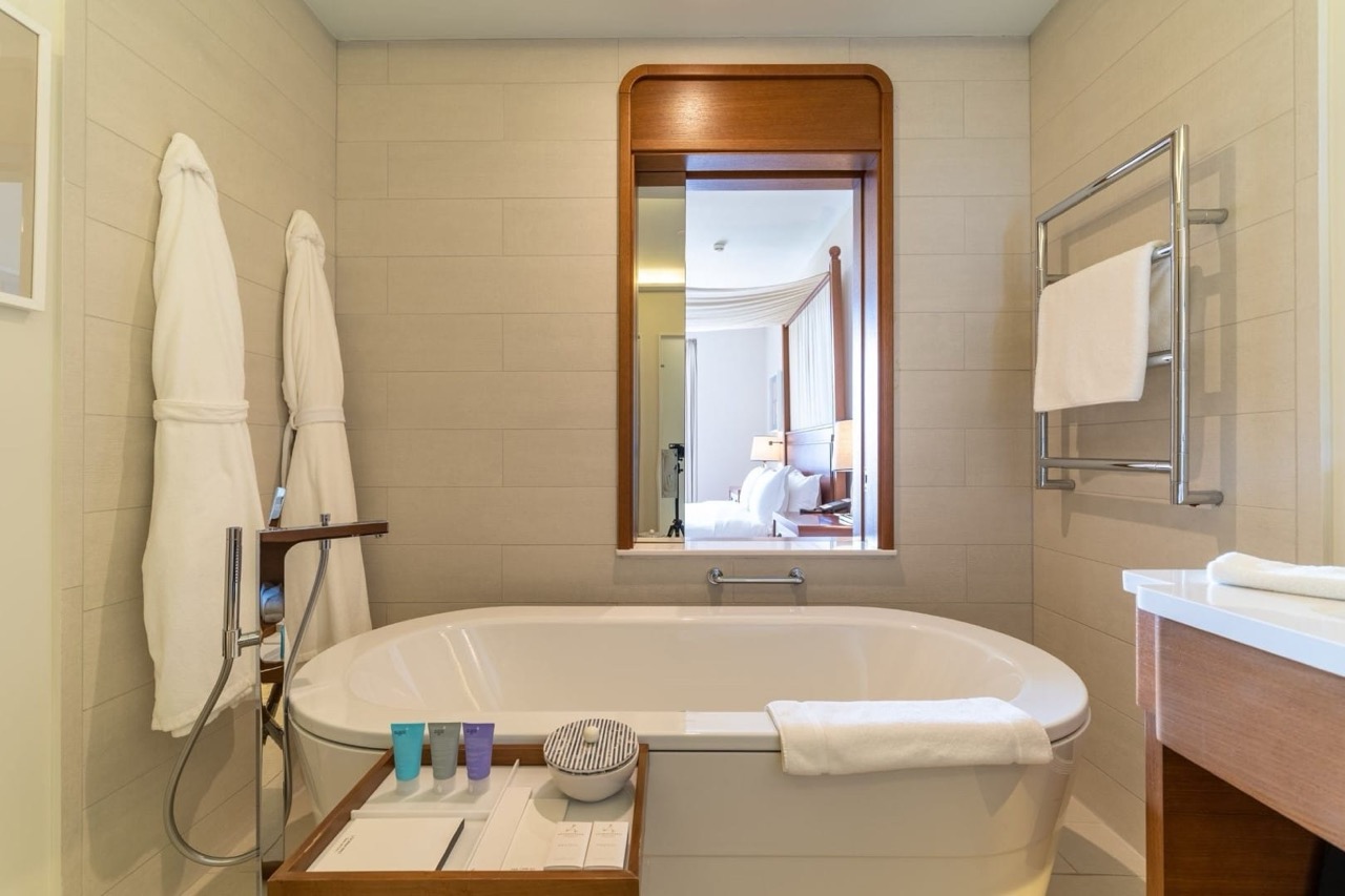 Modern bathroom in Porto Montenegro apartments, Tivat, Montenegro: bathtub, bathrobes, and a view of the bedroom.