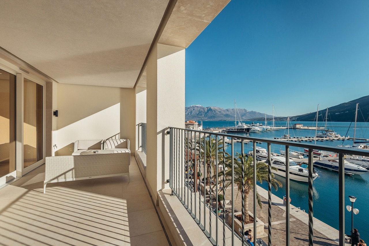 Terrace with furniture and a view of Portonovi Marina, Kumbor, Montenegro: a panorama of yachts, sea, and mountains in a luxury complex.
