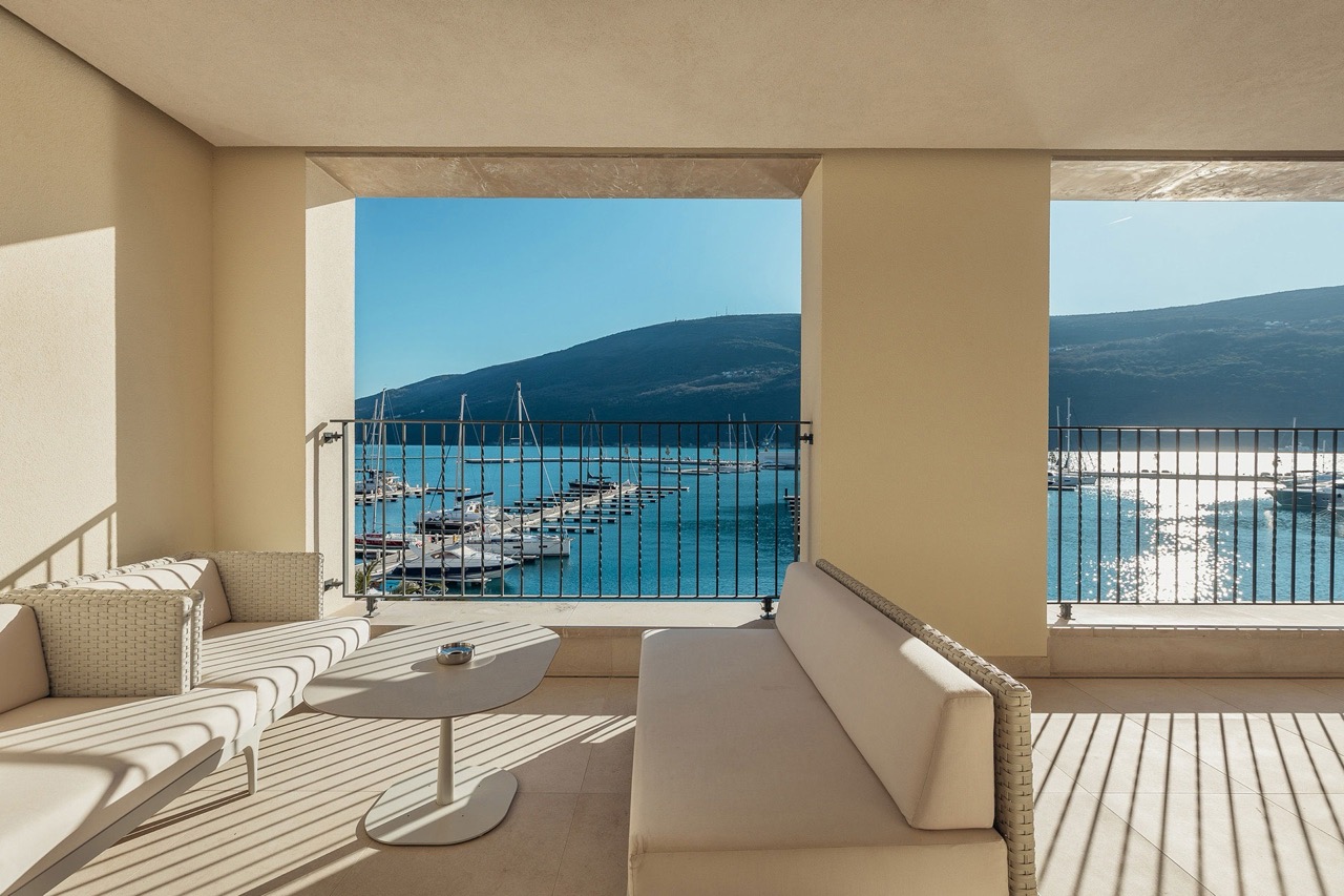Terrace with wicker furniture and a view of Portonovi Marina, Kumbor, Montenegro. Modern apartment with panoramic views.