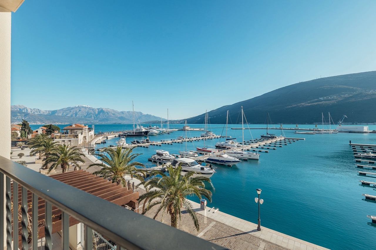 View from the apartment balcony in Portonovi, Kumbor, Montenegro: panoramic view of the yacht marina, mountains, and the Adriatic Sea.