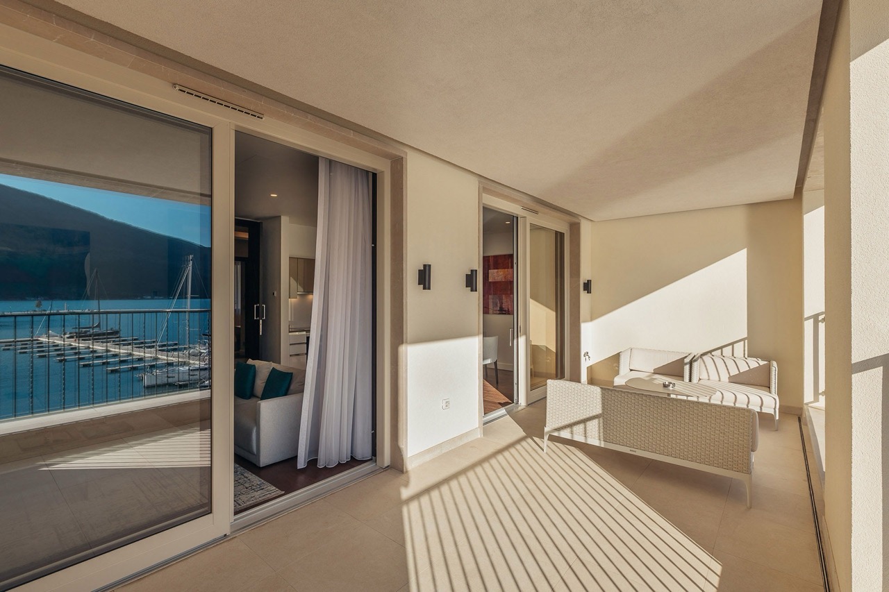 Spacious terrace with wicker furniture in an apartment in Portonovi, Kumbor, Montenegro, overlooking the yacht marina and the sea.