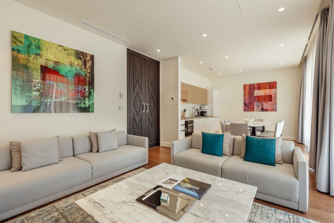 Modern living room with kitchen in Portonovi apartments, Kumbor, Montenegro: light furniture, marble table, and decor.