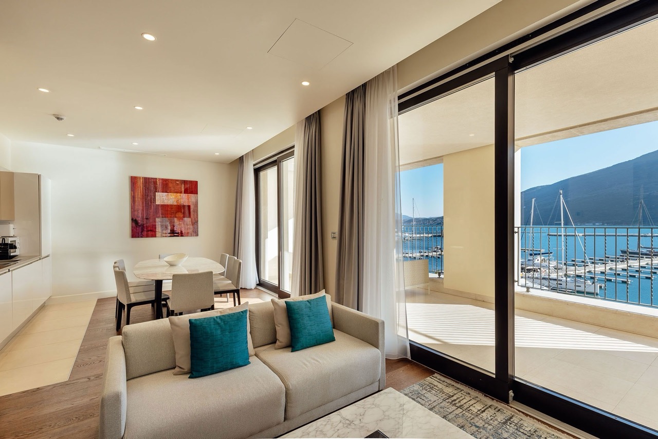 Living room with a view of the marina in an apartment in Portonovi, Kumbor, Montenegro: modern furniture, panoramic windows, and a terrace.