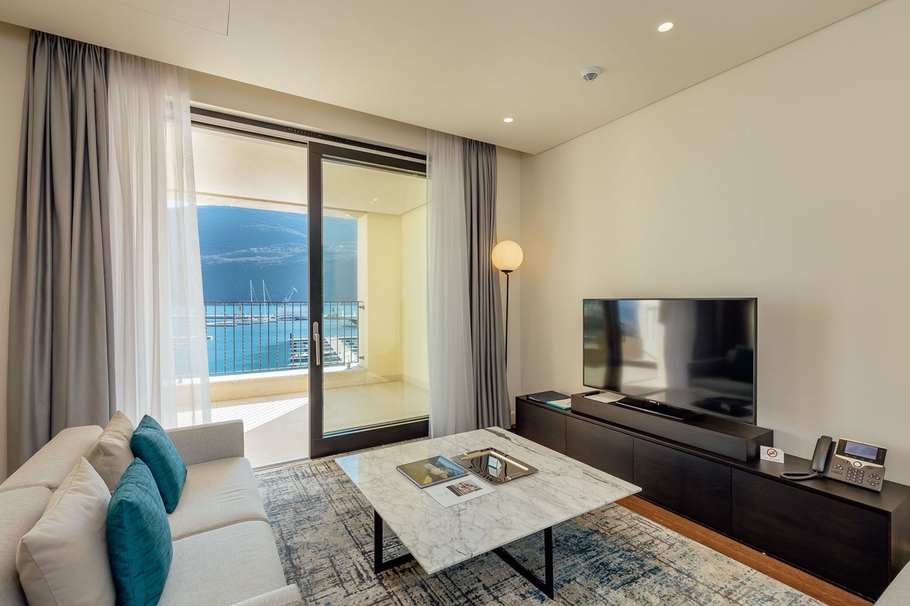 Living room in an apartment in Portonovi, Kumbor, Montenegro: modern furniture, a marble table, and a view of the marina with yachts.