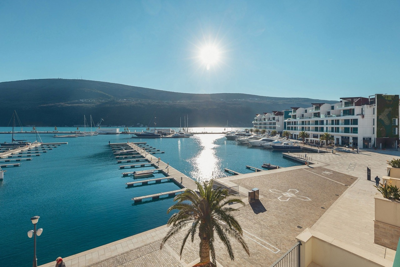 View of a modern marina and yachts in the upscale Portonovi complex, Kumbor, Montenegro. Sunny day, waterfront promenade.