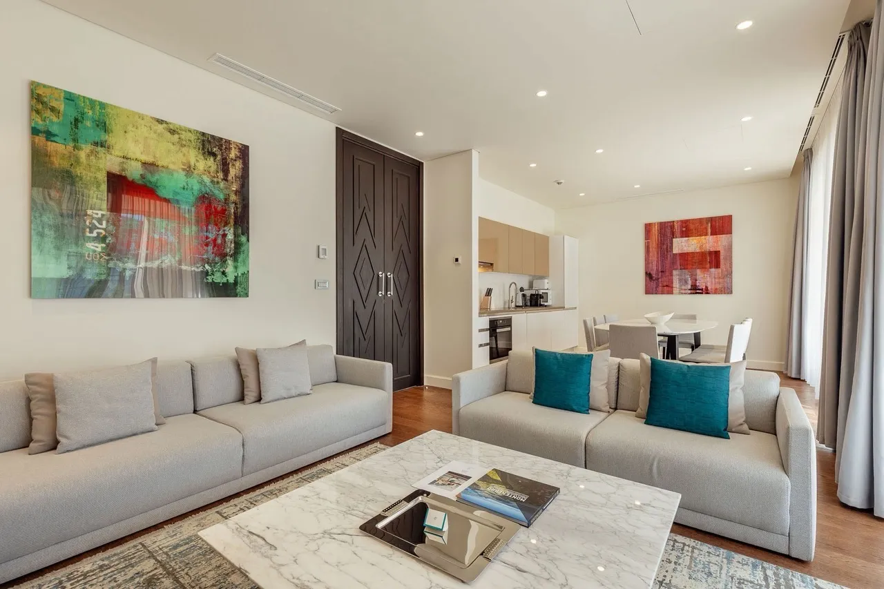 Bright living room with grey sofas, a marble coffee table, and abstract wall art visible.