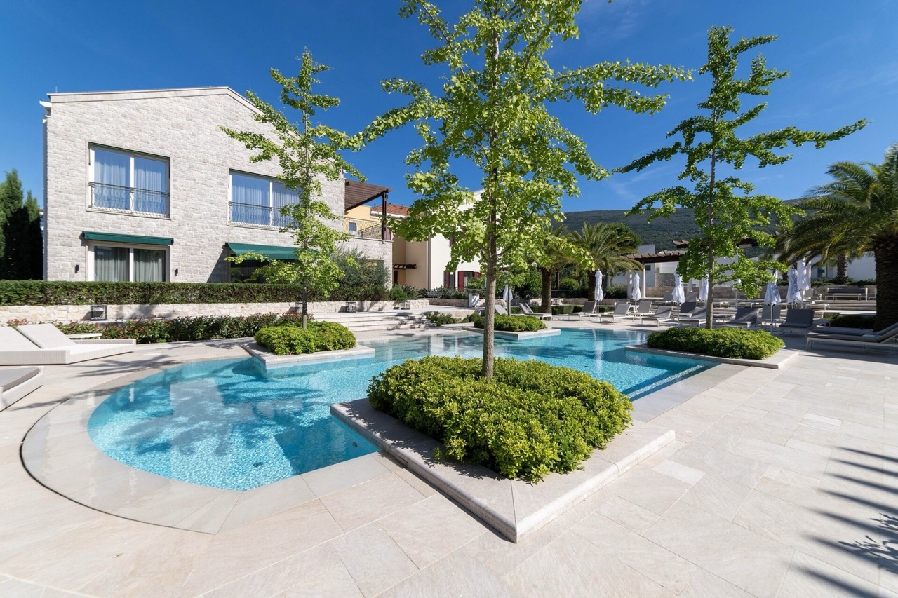 An outdoor pool with landscaping and sun loungers at the Portonovi residential complex, Kumbor, Montenegro.