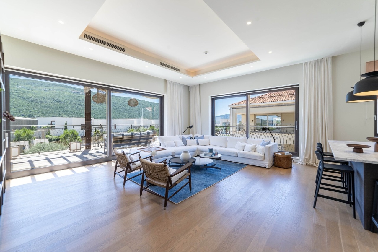 Modern living room in Portonovi, Kumbor, Montenegro: panoramic windows, light-colored furniture, terrace with mountain views.