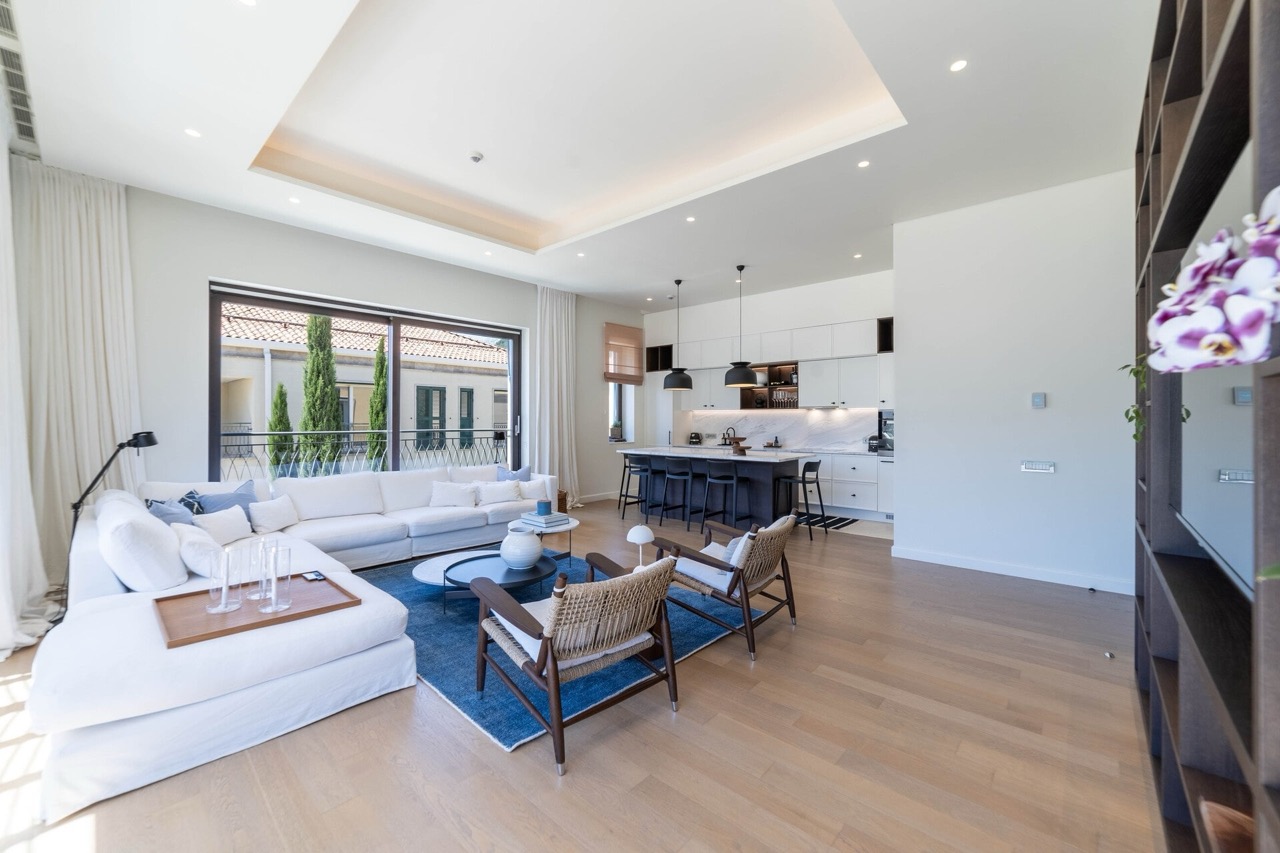 Modern living room with kitchen in an apartment in Portonovi, Kumbor, Montenegro: white sofa, panoramic windows, and stylish decor.