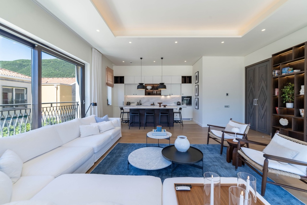 Modern living room with kitchen in Portonovi apartments, Kumbor, Montenegro: white sofa, marble island, and mountain view.