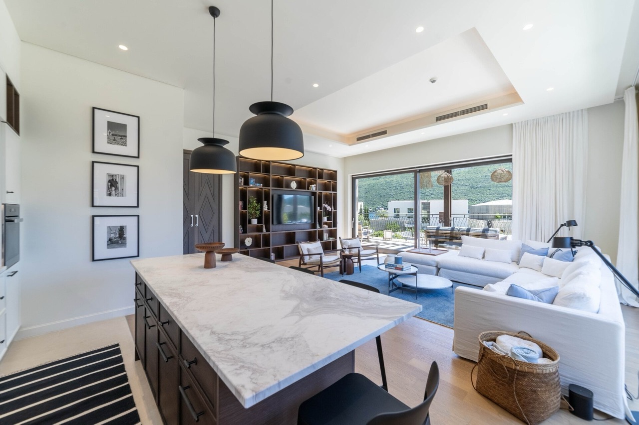 Modern living room with kitchen in an apartment in Portonovi, Kumbor, Montenegro: marble island, light furniture, and mountain view.