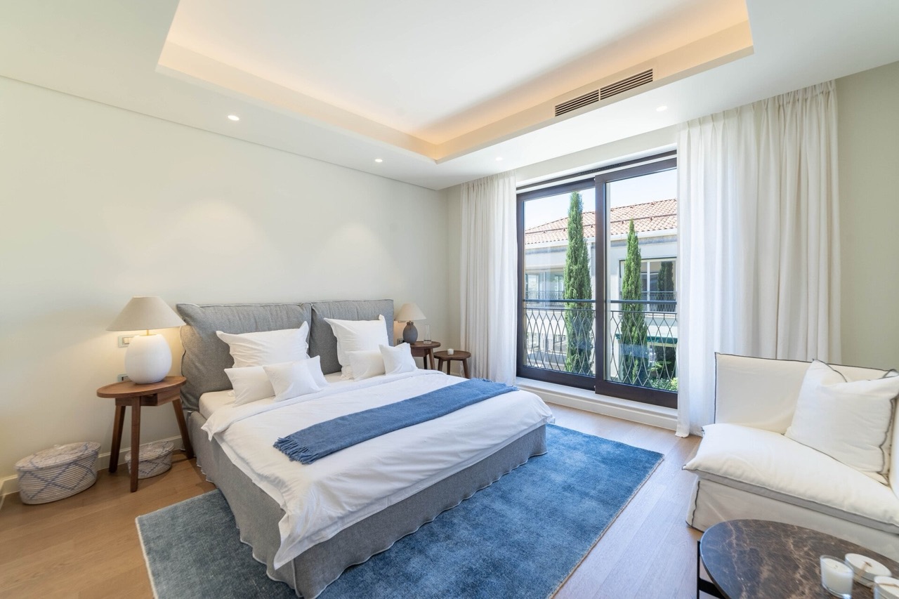 Modern bedroom in an apartment in Portonovi, Kumbor, Montenegro: double bed, panoramic windows, and a view of cypress trees.
