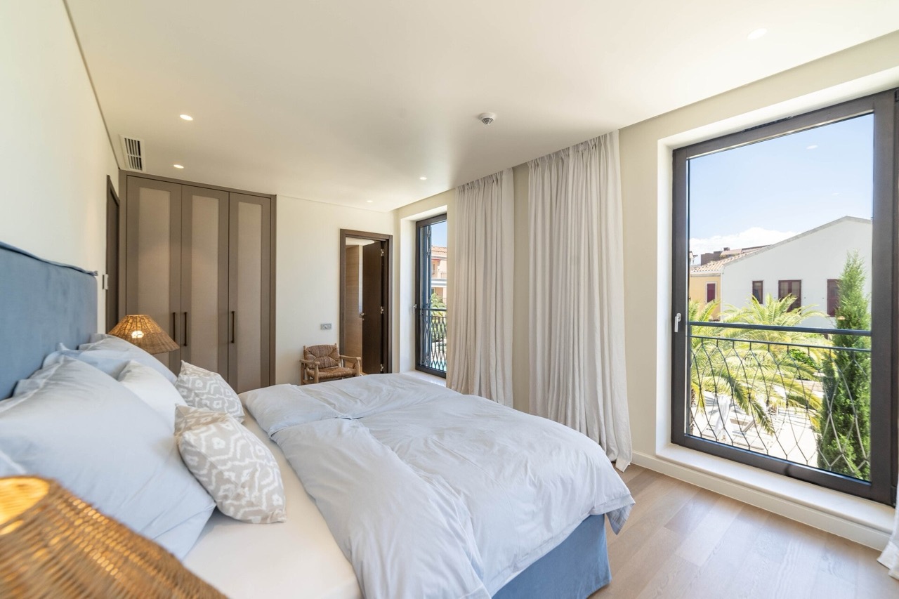 Modern bedroom in an apartment in Portonovi, Kumbor, Montenegro: double bed, built-in wardrobe, and a view of palm trees.
